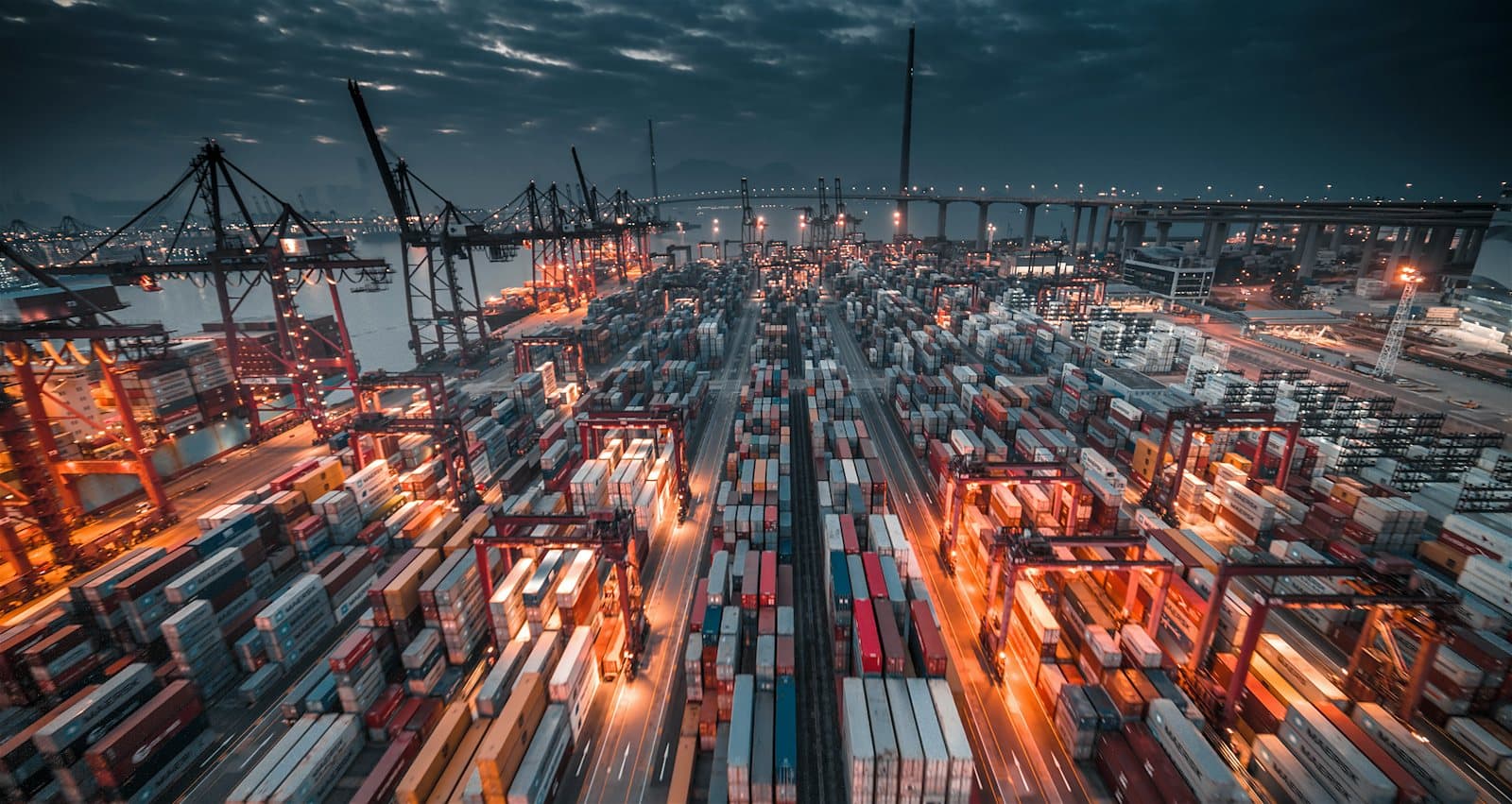 Container terminal with stacked containers and cranes at dusk